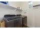Laundry room with front loading washer and dryer and overhead shelving at 12956 N 152Nd Ave, Surprise, AZ 85379