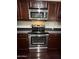 Close up of the stainless steel oven and microwave nestled in the rich, dark cabinetry at 1304 S Owl Dr, Gilbert, AZ 85296