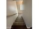 Carpeted stairway with wooden handrail descending to the lower level, showcasing neutral tones at 1304 S Owl Dr, Gilbert, AZ 85296