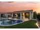 Stunning backyard featuring covered patio with furniture, pool with lights, and green turf at 13616 W Junipero Dr, Sun City West, AZ 85375