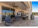 This covered patio includes a ceiling fan, outdoor seating, a TV, and access to the pool at 13616 W Junipero Dr, Sun City West, AZ 85375