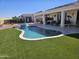Inviting backyard oasis features a sparkling pool, spa, covered patio, and lush artificial turf for easy maintenance at 13616 W Junipero Dr, Sun City West, AZ 85375