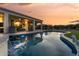 Backyard pool and spa with outdoor living space, covered patio and lush artificial grass at sunset at 13616 W Junipero Dr, Sun City West, AZ 85375