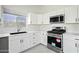 Modern kitchen with white cabinets, stainless steel appliances, quartz countertops, and a large window at 14398 W Marcus Dr, Surprise, AZ 85374