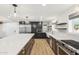 Open kitchen boasting sleek countertops, island, stainless steel fridge, and ample cabinet space, with modern lighting fixtures at 1610 E Mclellan Rd, Mesa, AZ 85203
