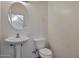 Clean half-bathroom featuring a pedestal sink, round mirror, and toilet at 1713 S 117Th Dr, Avondale, AZ 85323