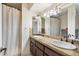 Bathroom featuring double sinks with tile countertops, wooden cabinets, and a large mirror at 18256 N 75Th Ave, Glendale, AZ 85308