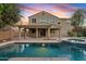 Evening shot of a tranquil backyard with a sparkling pool, spa, and a covered patio at 2670 E Parkview Dr, Gilbert, AZ 85295
