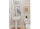 Bright and airy powder room with a pedestal sink, a modern mirror, and a view of the staircase at 2670 E Parkview Dr, Gilbert, AZ 85295