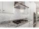 Elegant kitchen design showcases white cabinets, granite countertops, stainless steel range hood, and a modern tile backsplash at 29606 N Tarragona Dr, Peoria, AZ 85383