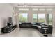 Bright open living room featuring large windows overlooking the pool and a black leather wraparound couch at 29606 N Tarragona Dr, Peoria, AZ 85383