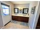 Bathroom with double sinks, wood cabinets, tile floors, and access to outside patio at 3807 E Altadena Ave, Phoenix, AZ 85028