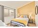 Bedroom featuring a metal bed frame, wood floors, and sunny yellow accent wall at 406 E Washington Ave # C, Gilbert, AZ 85234