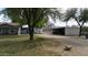 A backyard showcases mature shade trees and several outbuildings, including a barn, adding character and utility to the property at 4311 W Siesta Way, Laveen, AZ 85339