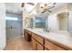 Bathroom featuring a double sink vanity, oversized mirrors, tiled floors and a large glass shower at 4537 E Sunnyside Ln, Phoenix, AZ 85032