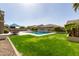 Well-manicured backyard with green lawn, pool, and travertine pavers at 4884 S Hemet St, Gilbert, AZ 85298