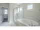 Bright bathroom featuring a glass shower, soaking tub, and marble tile surround at 6418 N 17Th St, Phoenix, AZ 85016