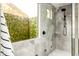 Walk-in shower featuring a natural stone tile surround, modern shower fixtures, and a window with lush views at 6438 E Montreal Pl, Scottsdale, AZ 85254