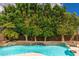 Inviting swimming pool with mature trees and a natural stone waterfall feature at 6438 E Montreal Pl, Scottsdale, AZ 85254