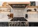 Close up of the gourmet stainless steel range, open shelves, and sleek backsplash at 6438 E Montreal Pl, Scottsdale, AZ 85254
