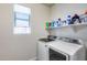 Functional laundry room with modern washer and dryer, bright window, and ample shelving for storage at 7363 E Plata Ave, Mesa, AZ 85212