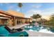 Resort-style backyard featuring a sparkling pool, lounge chairs, mature vegetation, and covered patio at 9716 E Mariposa Grande Dr, Scottsdale, AZ 85255