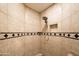Close-up of a tiled shower featuring a showerhead, a niche, and a decorative tile border at 9716 E Mariposa Grande Dr, Scottsdale, AZ 85255