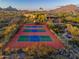 Aerial view showcasing tennis court nestled among desert landscaping with mountains in the background at 9716 E Mariposa Grande Dr, Scottsdale, AZ 85255
