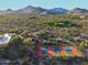 Aerial view of neighborhood tennis courts and desert landscape with distant mountain views in a residential area at 9716 E Mariposa Grande Dr, Scottsdale, AZ 85255