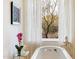 Elegant bathroom with a standalone tub and natural light streaming through the sheer curtains at 10244 E Hualapai Dr, Scottsdale, AZ 85255