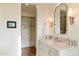 Bathroom with marble vanity, chrome fixtures, decorative sconces, and a walk-in closet at 10244 E Hualapai Dr, Scottsdale, AZ 85255