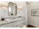 Bright powder room featuring white cabinetry, marble countertop, stylish sconces, and decorative mirror at 10244 E Hualapai Dr, Scottsdale, AZ 85255