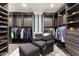 Well-organized walk-in closet boasts custom shelving and hanging rods with a seating area at 10244 E Hualapai Dr, Scottsdale, AZ 85255