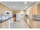 Bright kitchen featuring modern appliances, tile flooring, and light wood cabinets at 10816 W Hatcher Rd, Sun City, AZ 85351