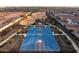 Outdoor basketball court with modern blue surface, lights and covered seating area in a Gathering-friendly community at 10823 W Polk St, Avondale, AZ 85323