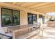 Covered back patio featuring travertine floors, outdoor grilling area, exterior TV, and sliding glass door at 10903 E Sahuaro Dr, Scottsdale, AZ 85259