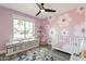 Adorable Bedroom featuring flower wall design, a white crib and shelving for toys and books, and a colorful area rug at 10903 E Sahuaro Dr, Scottsdale, AZ 85259