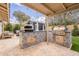 Outdoor kitchen with built-in BBQ, pizza oven, custom tile work and view of private backyard at 10903 E Sahuaro Dr, Scottsdale, AZ 85259