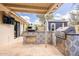 Backyard outdoor kitchen includes built-in gas grill and pizza oven on a travertine patio at 10903 E Sahuaro Dr, Scottsdale, AZ 85259