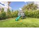 Backyard play structure with green slide surrounded by lush landscaping and green artificial turf at 10903 E Sahuaro Dr, Scottsdale, AZ 85259