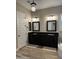 Bathroom featuring double vanity with black granite counter top, framed mirrors, and wood plank flooring at 11612 W Candelilla Way, Peoria, AZ 85383