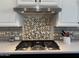 Close-up of a stainless steel stove top and decorative backsplash at 11612 W Candelilla Way, Peoria, AZ 85383