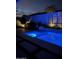 Swimming pool illuminated with blue lighting surrounded by an outdoor wall and shrubbery at 11612 W Candelilla Way, Peoria, AZ 85383