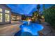 Pool with a waterfall feature, surrounded by lush landscaping, a fire pit, and an outdoor kitchen at 16060 S 4Th St, Phoenix, AZ 85048