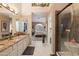 Well-lit bathroom featuring double sinks, granite countertop, and a tiled shower with glass door, creating a luxurious feel at 18932 N 89Th Way, Scottsdale, AZ 85255