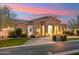 Beautiful stone home with a circular driveway and mature landscaping at dusk at 20216 E Sunset Ct, Queen Creek, AZ 85142