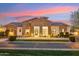 Stunning stone home with manicured landscaping and inviting entrance illuminated at twilight at 20216 E Sunset Ct, Queen Creek, AZ 85142