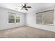 Inviting bedroom with carpet flooring, a ceiling fan, and ample natural light from the two windows at 2331 E Pecan Rd, Phoenix, AZ 85040