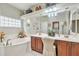 Bright bathroom with dual sinks, vanity seating, soaker tub, and decorator accents at 3032 N 160Th Ave, Goodyear, AZ 85395