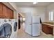 Bright laundry room featuring a washer, dryer, cabinetry, and a refrigerator adjacent to an open doorway at 3032 N 160Th Ave, Goodyear, AZ 85395